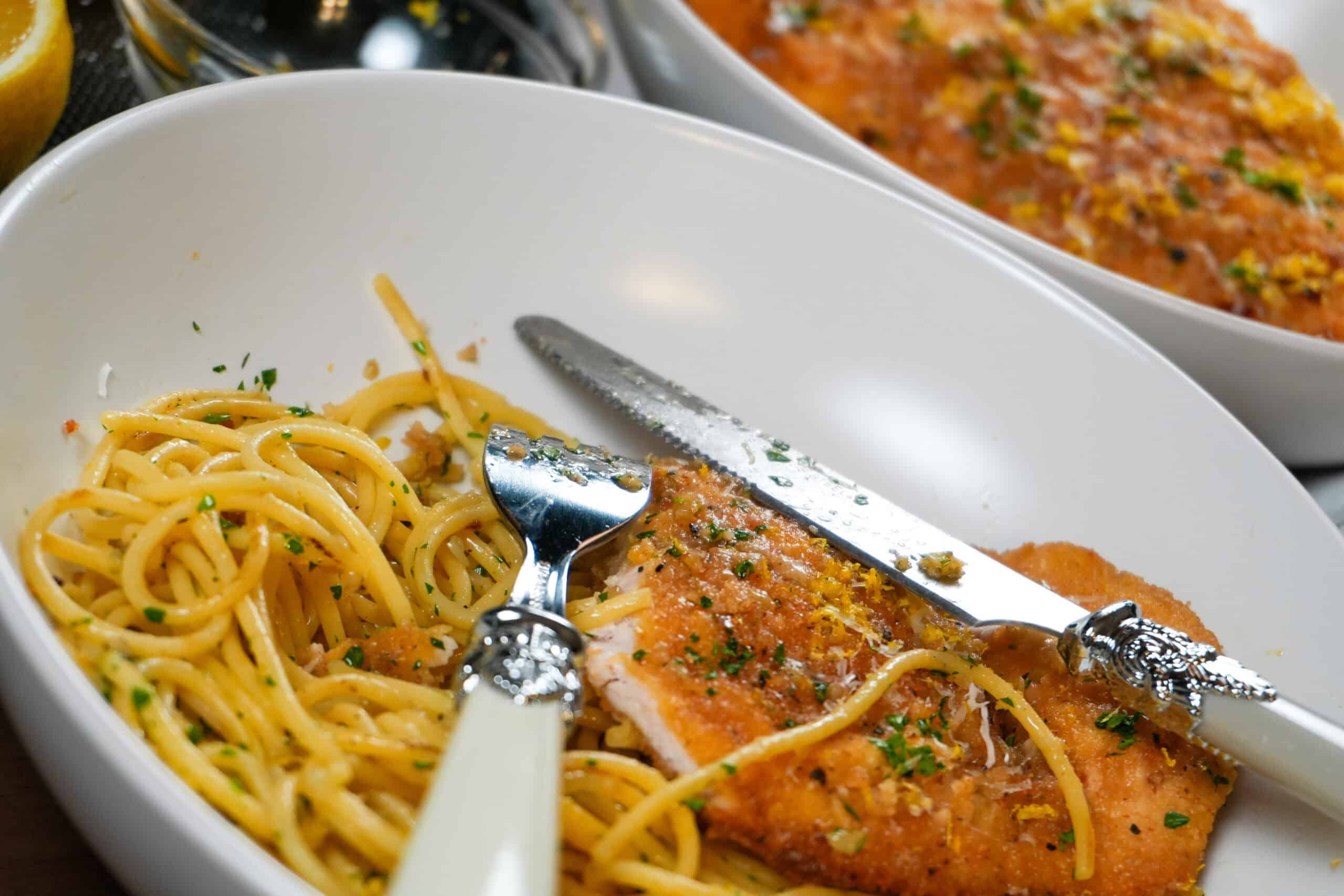 Delicious spaghetti and golden chicken cutlet served elegantly in a white bowl with herbs.